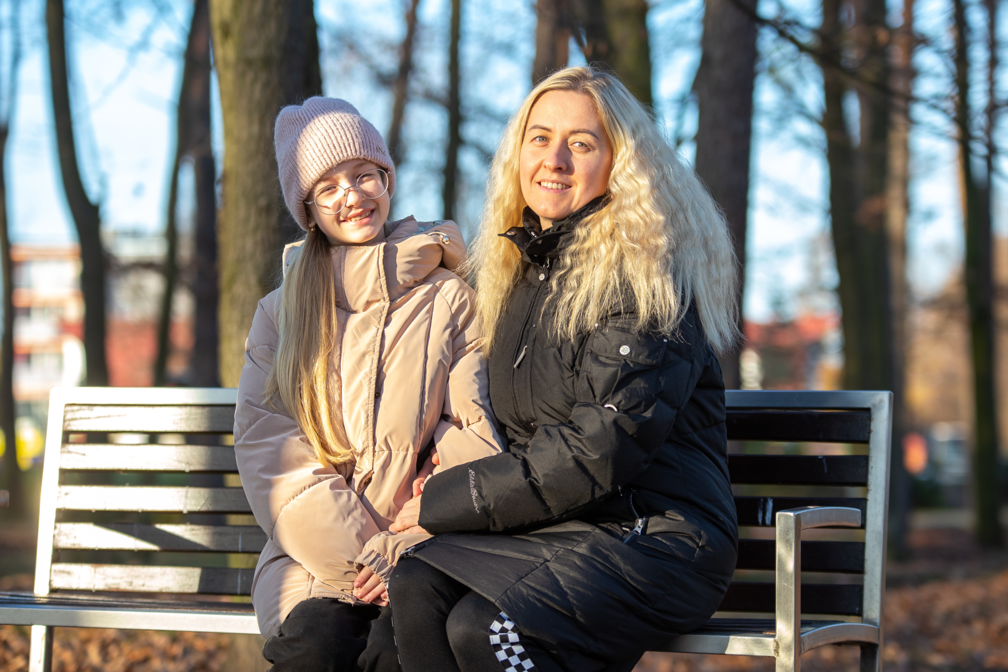 Marcharyta Boichuk and and her mother Iryna Polova sit together on a park bench.