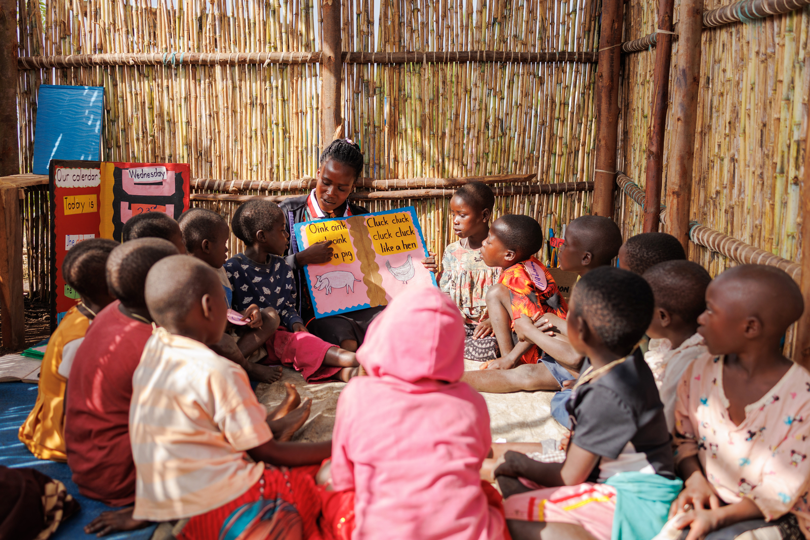 An informal early years centre in Kyaka II Refugee Settlement, Uganda. IMAGE CREDIT: Theirworld / Mara Mambo Media Tushemereirwe Angelica teaches Middle class (4-5Yrs) at Lion study area, Kaborogota B village- Kaborogota Zone. Teachers at the cluster points are known as Caregivers. Photography from Education Innovation Awards winner Children on the Edge (COTE)'s Cluster Points which provide Early Childhood Education at Kyaka II refugee settlement.